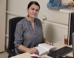 Zdjęcie Agnieszki Jaćwiąg siedzącej przy biurku, przy komputerze