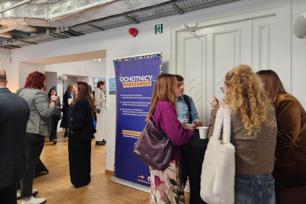 Uczestnicy wydarzenia zgromadzeni przy stolikach podczas przerwy kawowej.