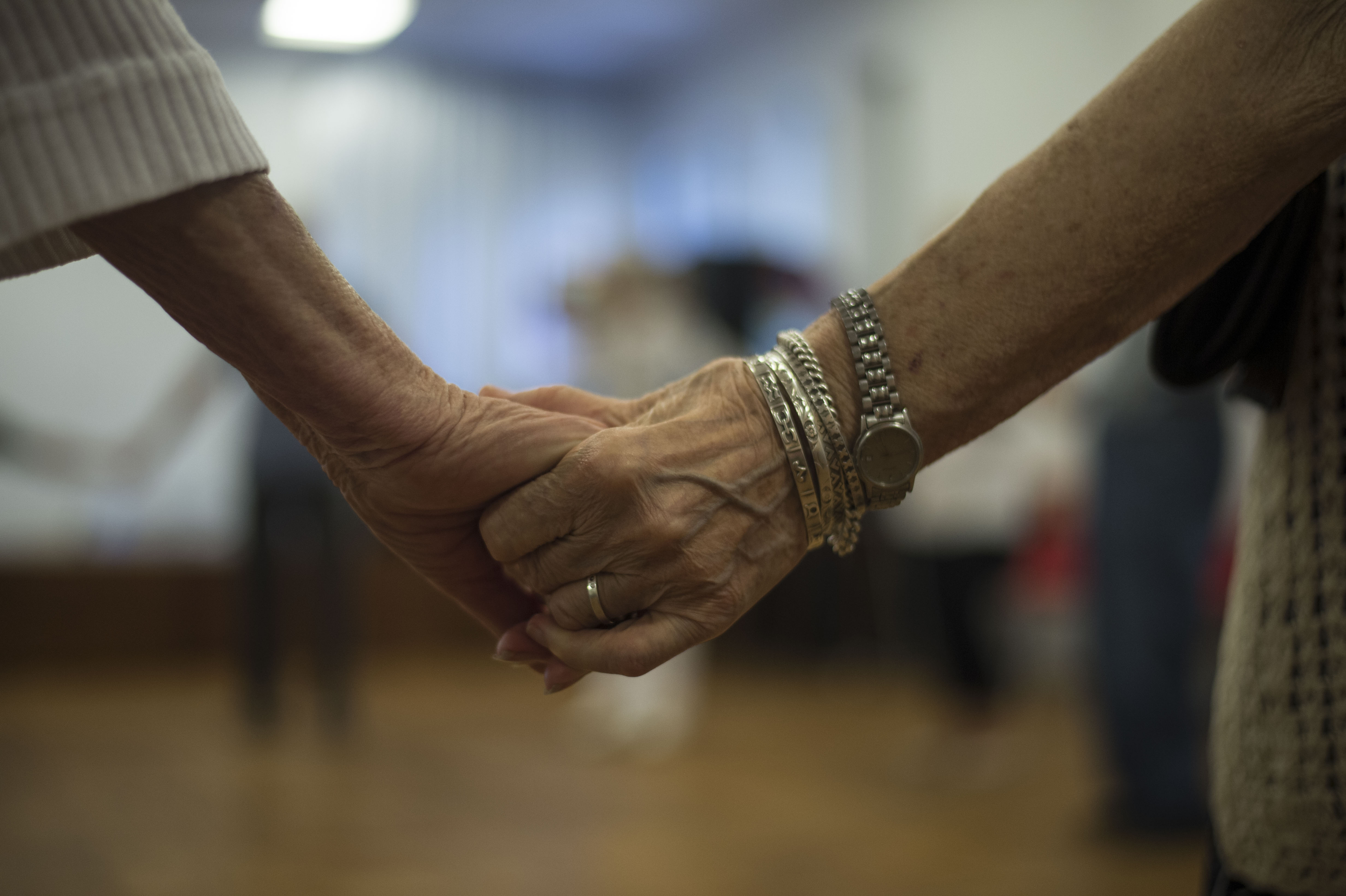 Dwie seniorki trzymają się za dłonie podczas zajęć tanecznych z Marcinem Hakielem