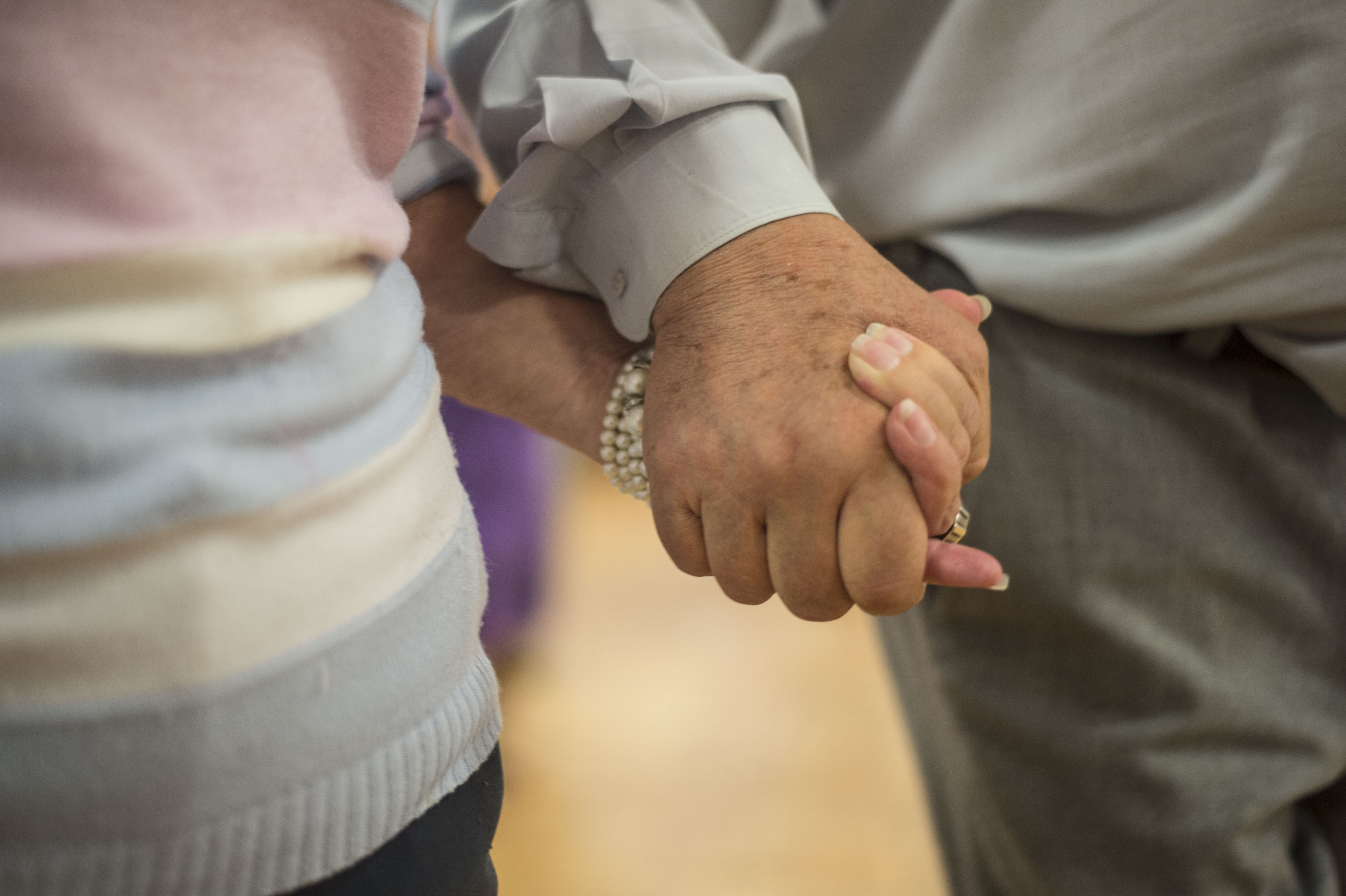 Para seniorów trzyma się za ręce podczas zajęć tanecznych z Marcinem Hakielem
