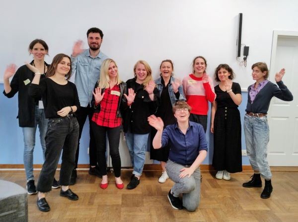 Zdjęcie grupowe uczestników i prowadzących szkolenie, 10 osób stoi na tle sali, machają ręką i uśmiechają się