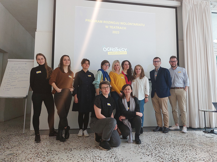 Kilkunastu uczestników szkolenia dla pracowników teatrów miejskich stojących przed rzutnikiem w sali Pawilonu Architektury ZODIAK