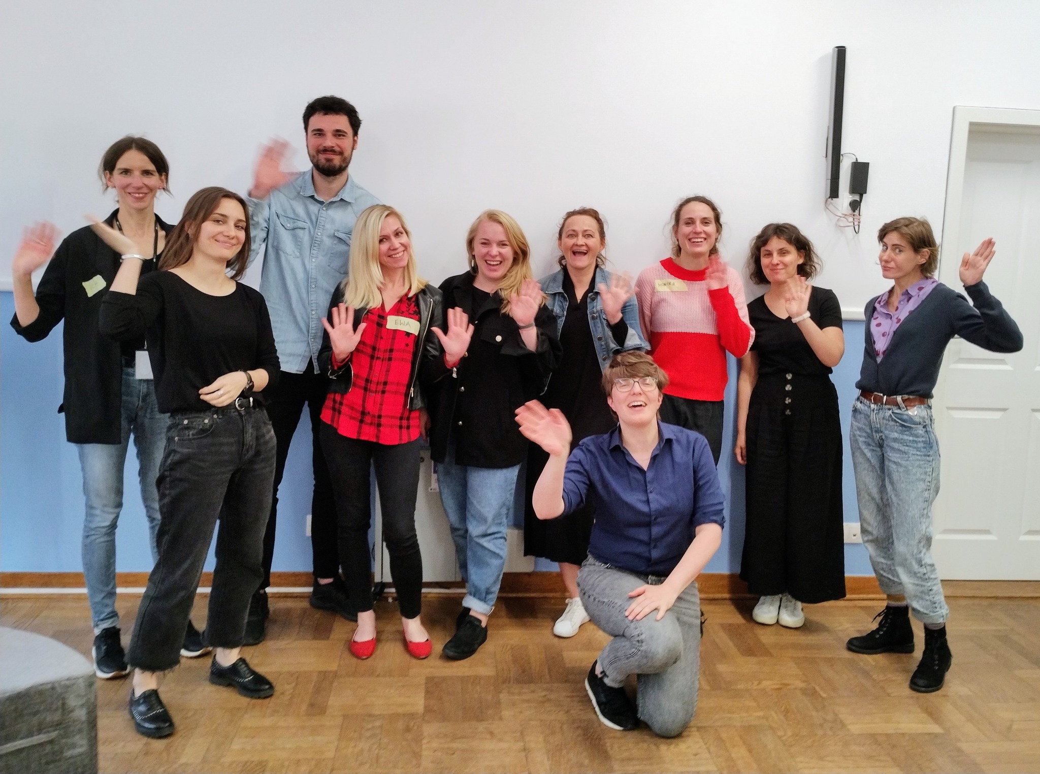 Grupa uśmiechniętych ludzi machających do kamery