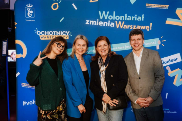 Zdjęcie przedstawia Małgorzatę Szumowską, Agnieszkę Kołodziejską, Katarzynę Dowbor, Michała Senka. W tle znajduje się niebieska plansza z napisem Wolontariat zmienia Warszawę